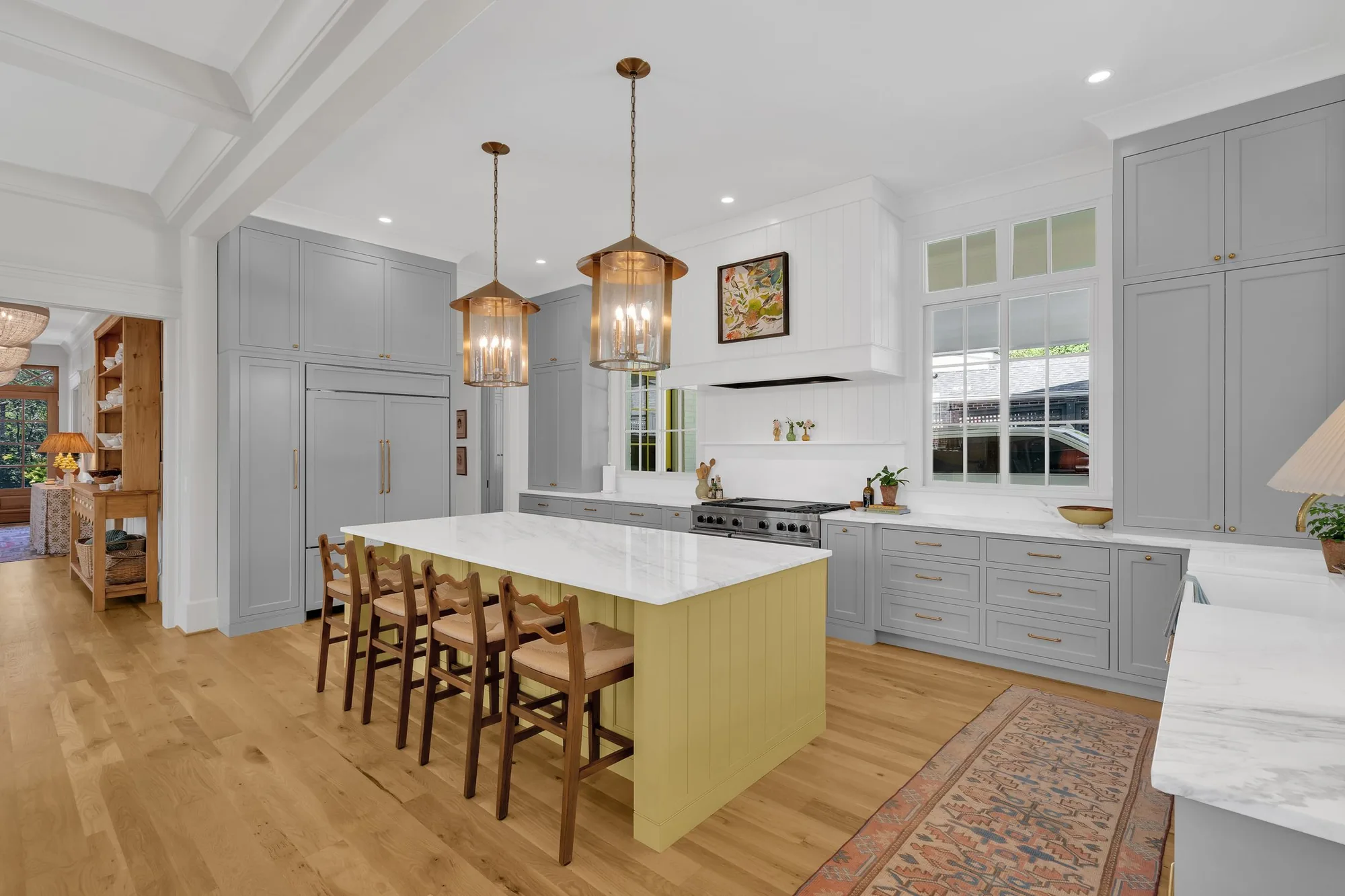 A large custom kitchen with painted cabinetry, a marble island and hanging lanterns