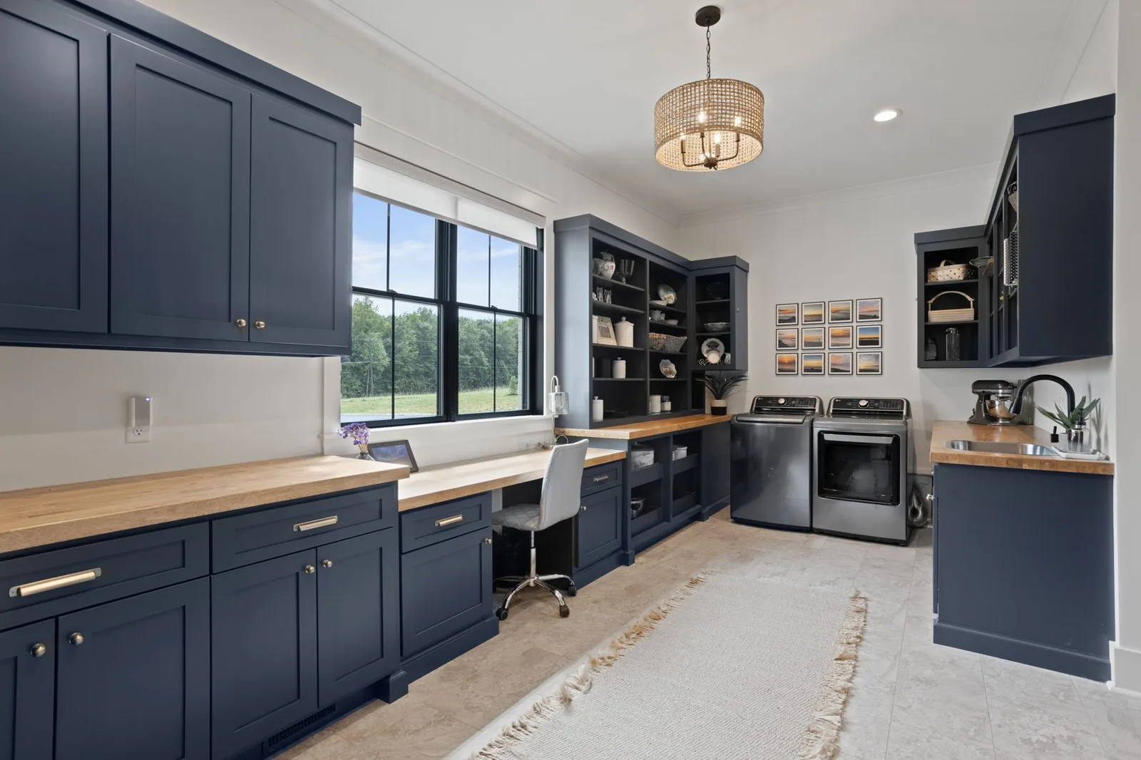 Navy blue laundry and workspace cabinetry with butcher block counters and a window desk