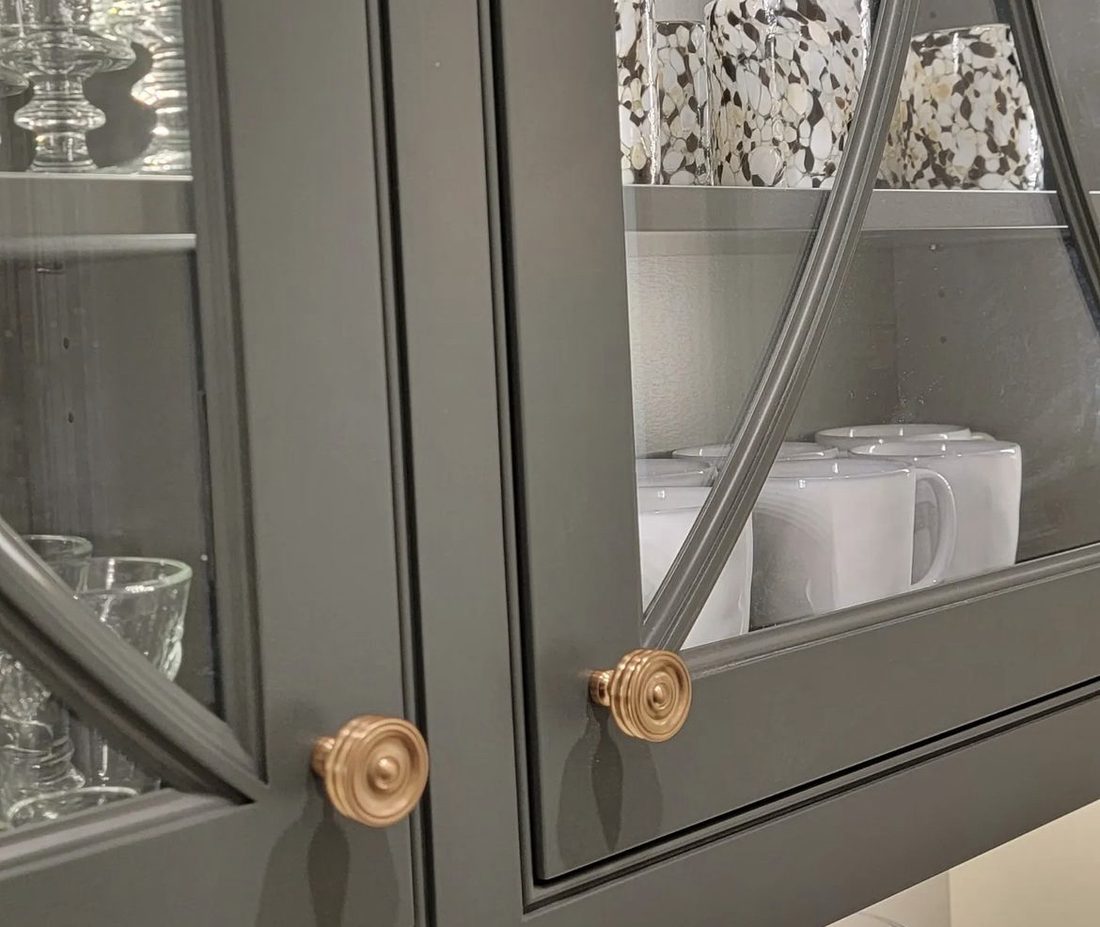 Dark green grey glass front cabinet doors with arched muntins and brass knobs