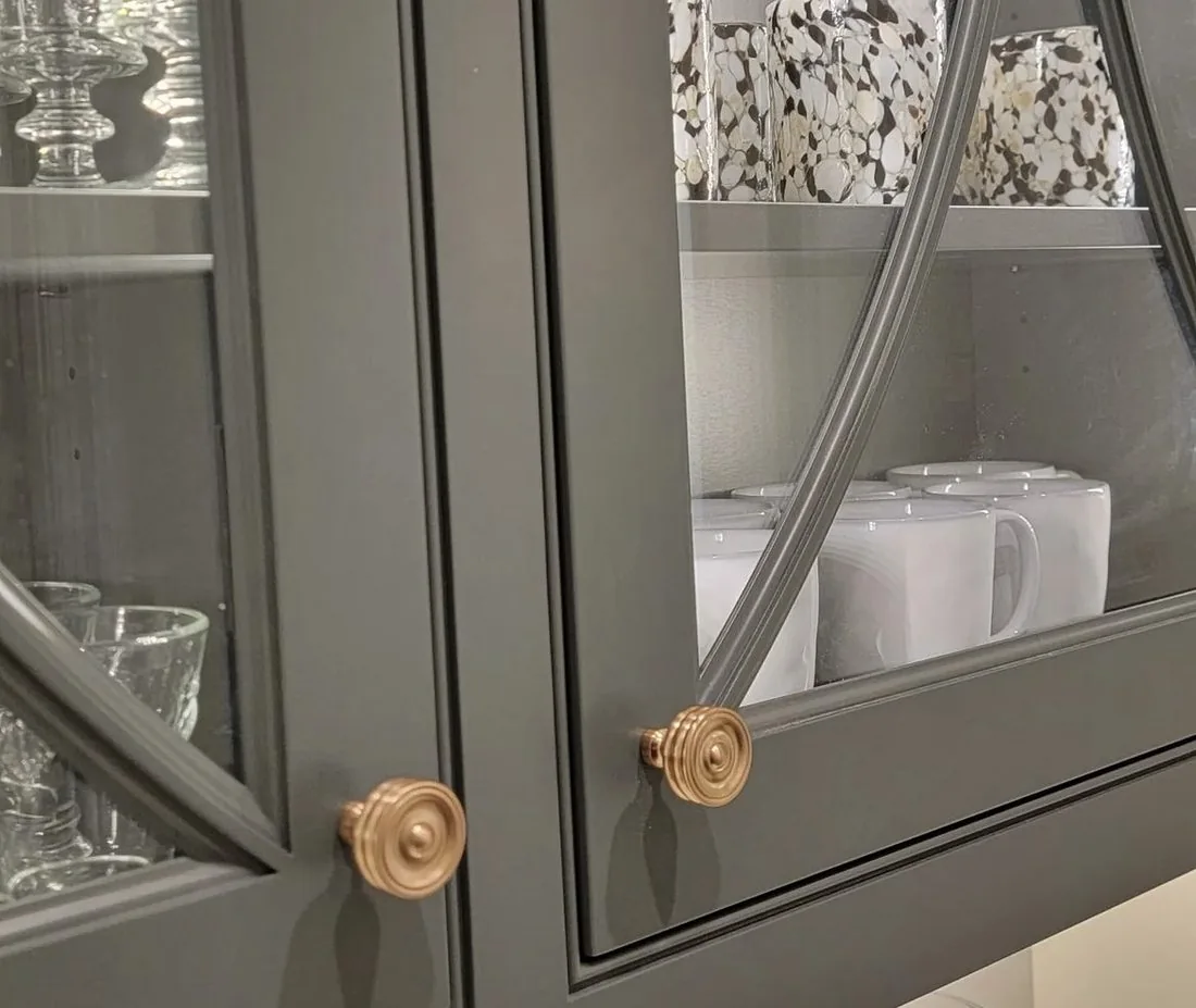 Dark green grey glass front cabinet doors with arched muntins and brass knobs