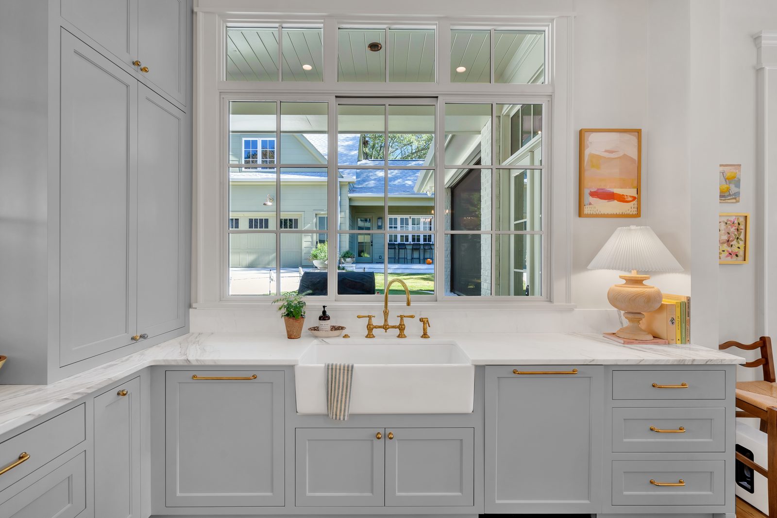 Grey cabinetry around a farmhouse sink under a divided light window