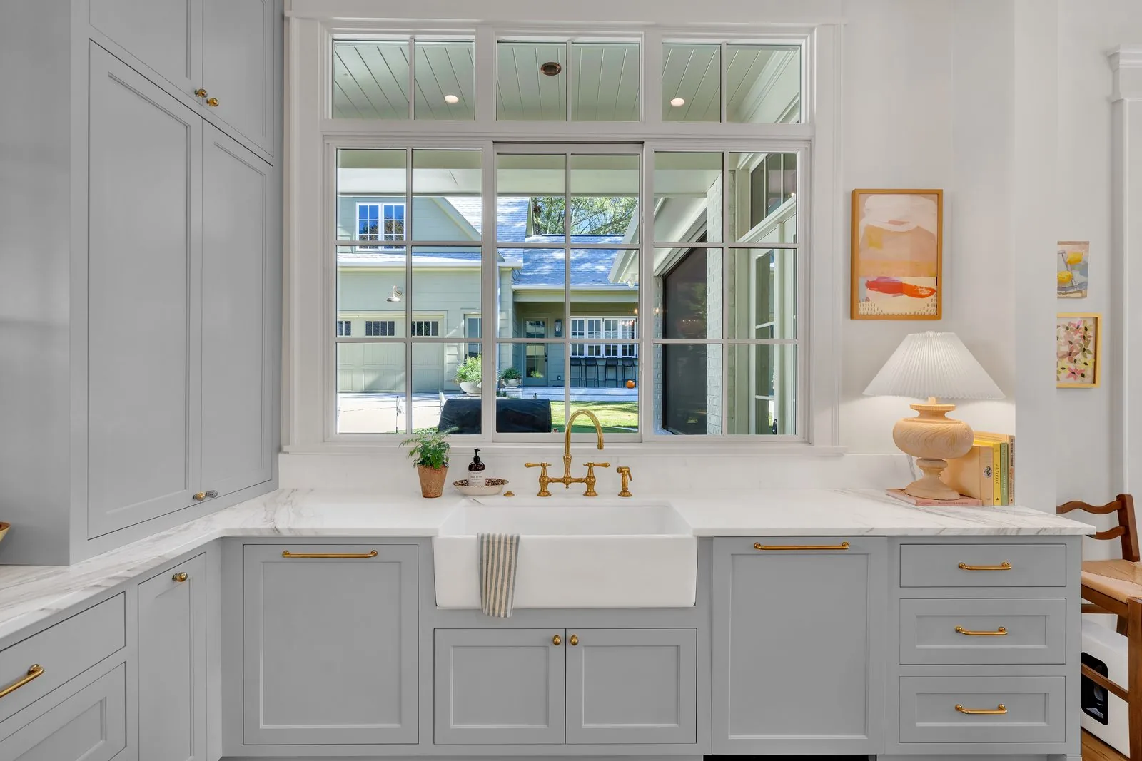 Grey cabinetry around a farmhouse sink under a divided light window