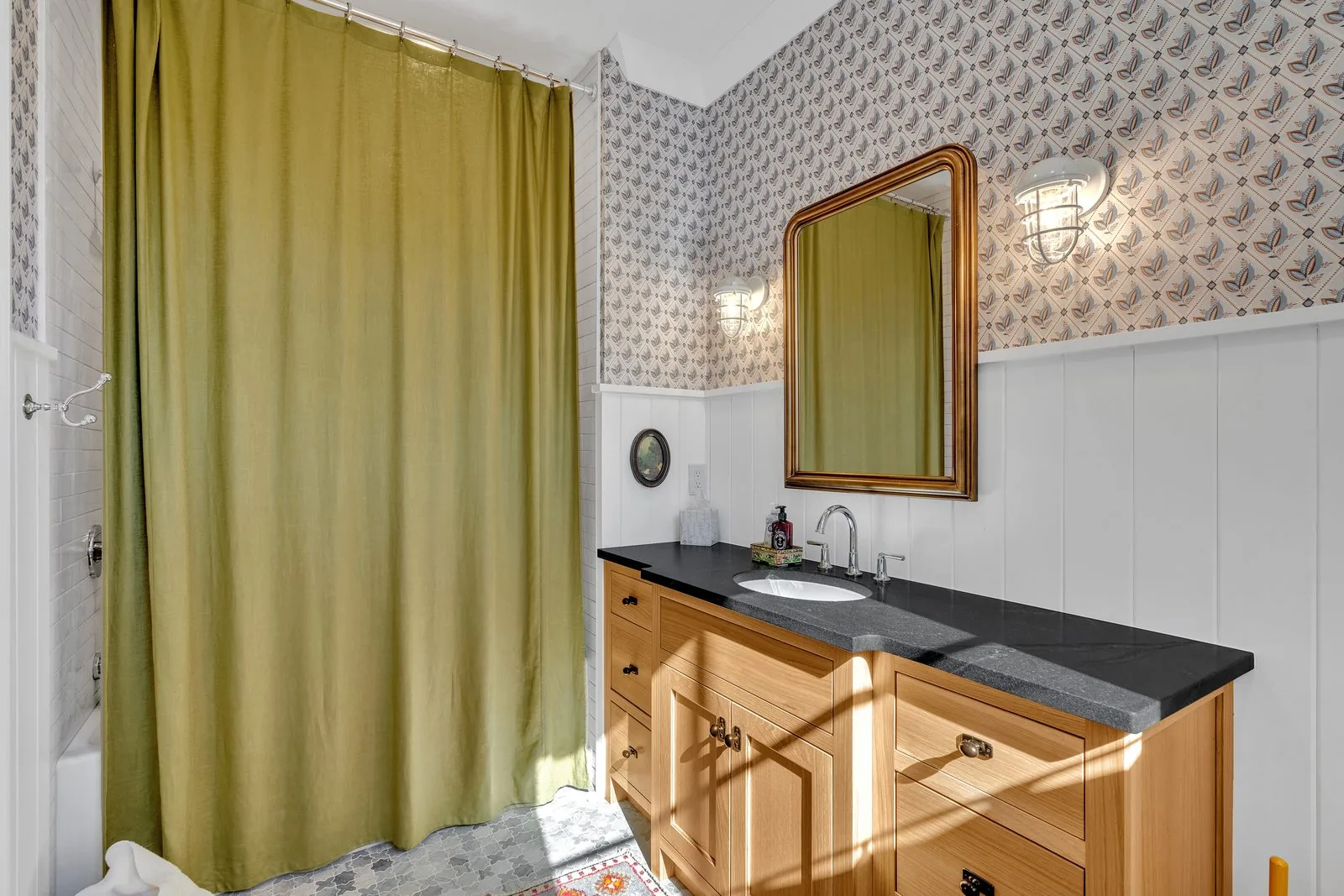Bath with an oak vanity, dark stone top and a tiled shower