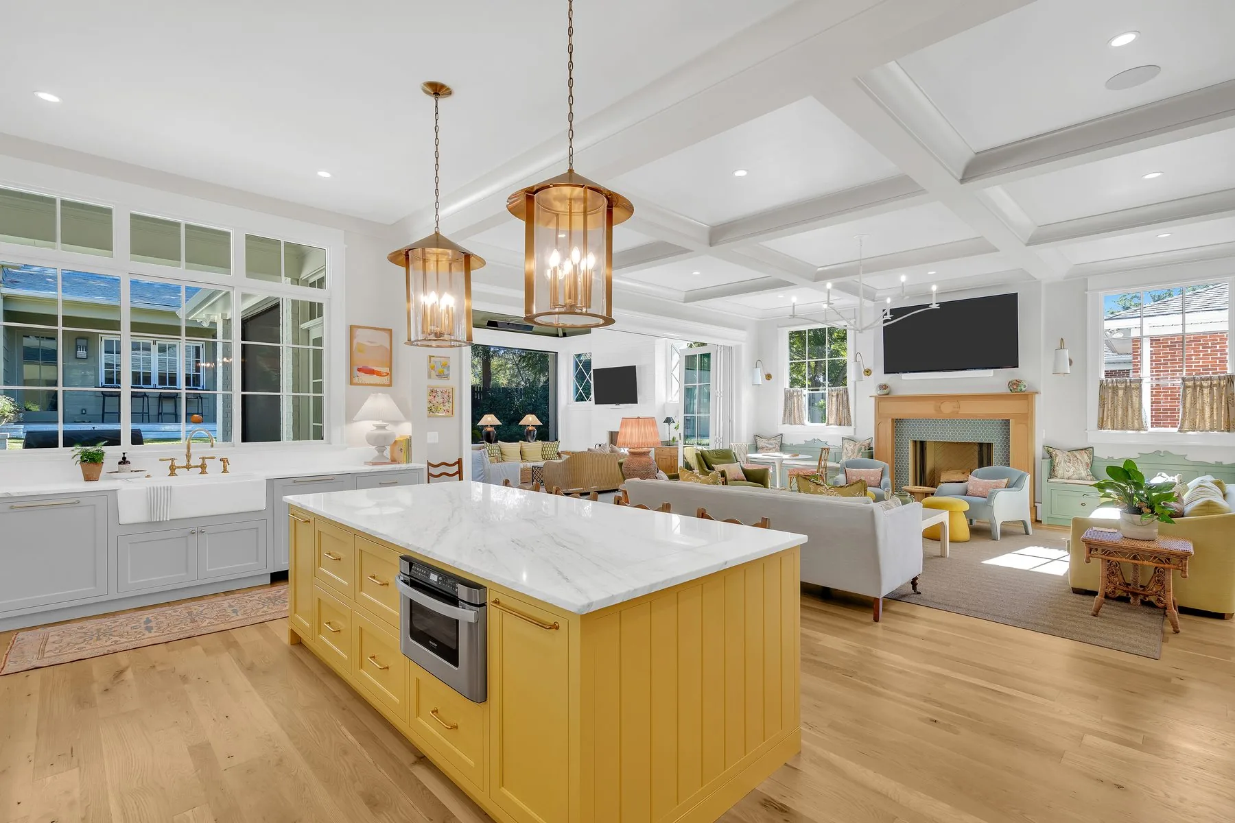Open kitchen with a painted yellow island, marble top and coffered ceiling